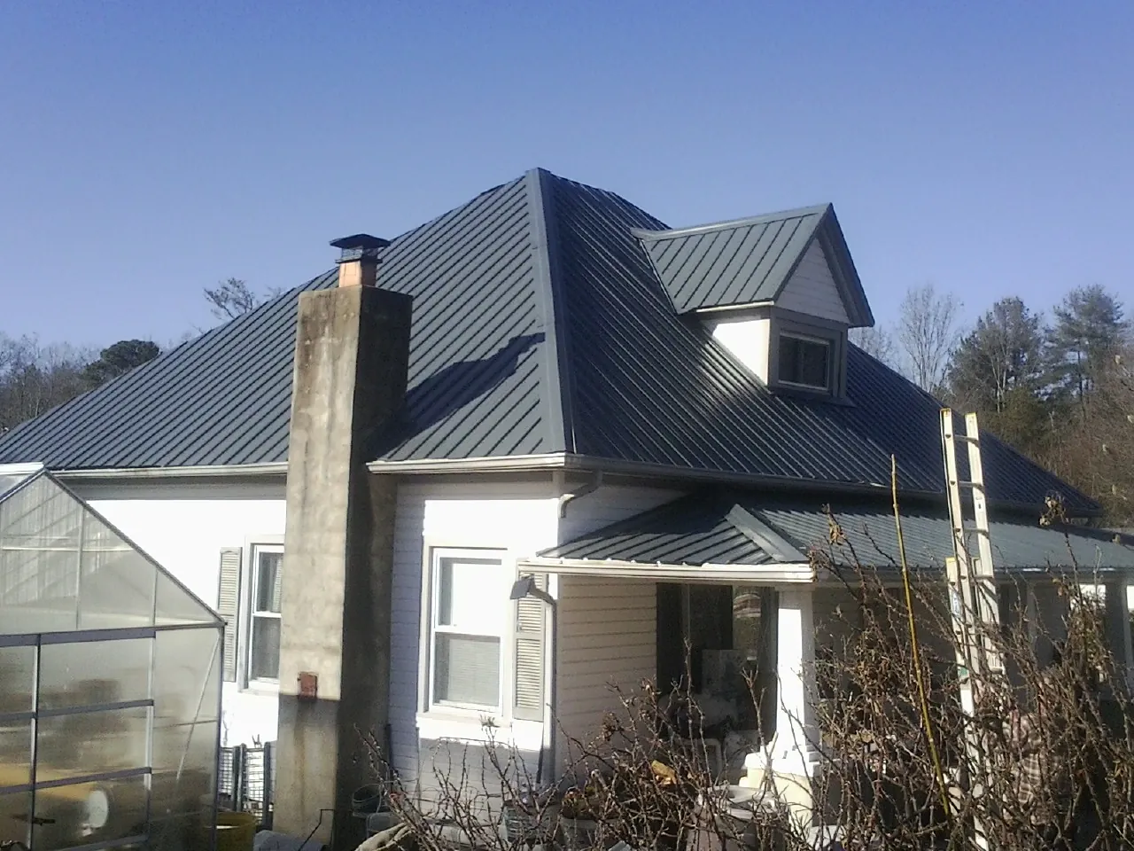 Dark blue standing seam metal roof on a white farmhouse with dormer — Slate & Tile Roof Repair by Roofing Brothers in Countyline