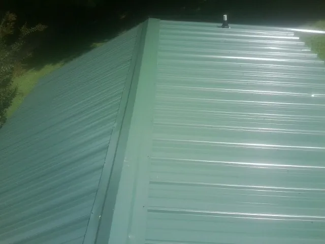 New green metal panels meeting at the ridge of a roof — Flat Roof Repair work by our crew in Countyline