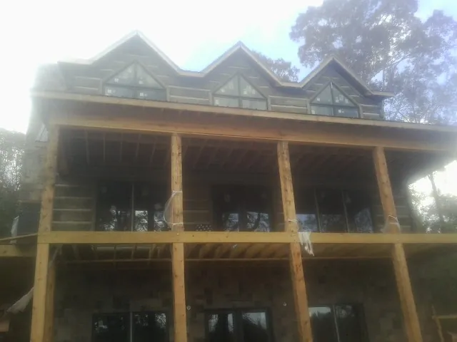 Dormers and porch framing on a large log home under construction — Roof Coating work by our crew in Countyline