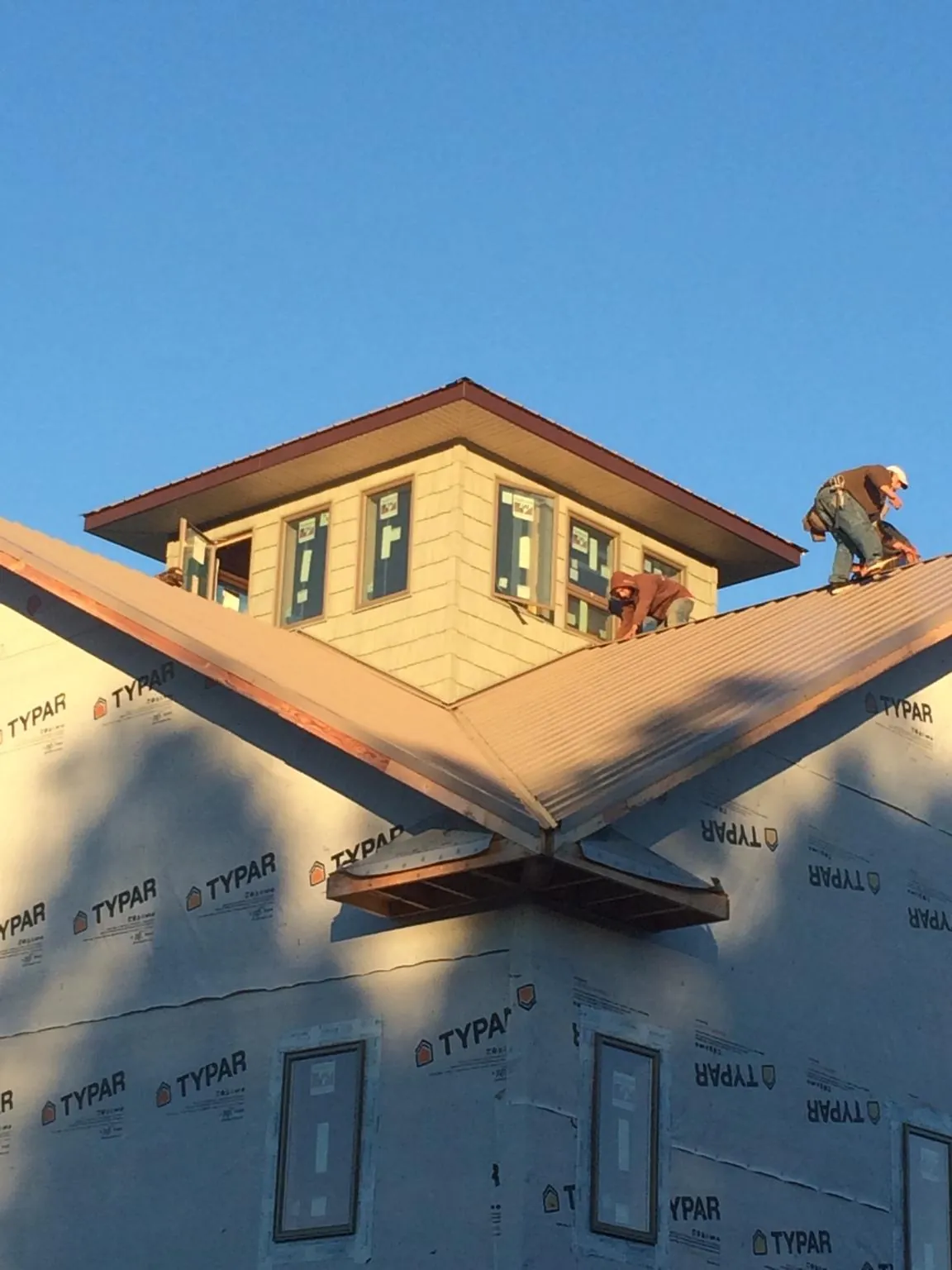 Roofers working around a rooftop cupola on a new metal roof at sunset — Roof Waterproofing in Countyline by Roofing Brothers